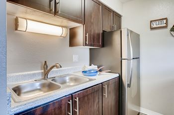 A kitchen with a sink, refrigerator, and cabinets.